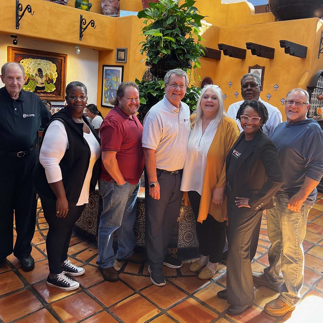 Group photo of members of the Evolution Foundation standing and smiling in restaurant with a tile floor.